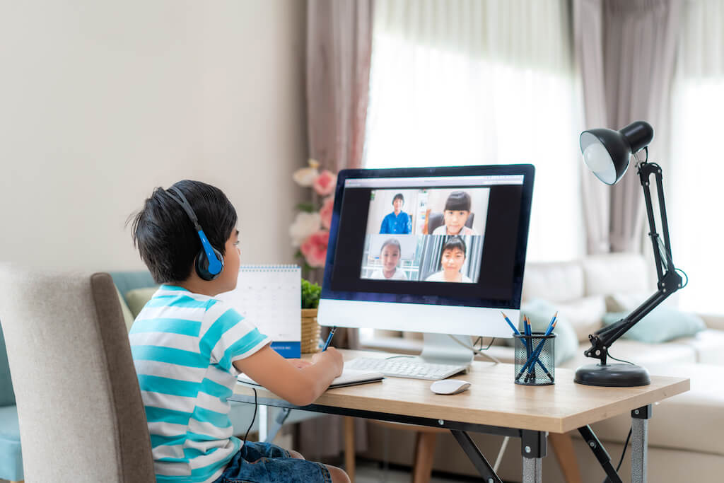 Un garçon assis devant un iMac participant à un cours en direct