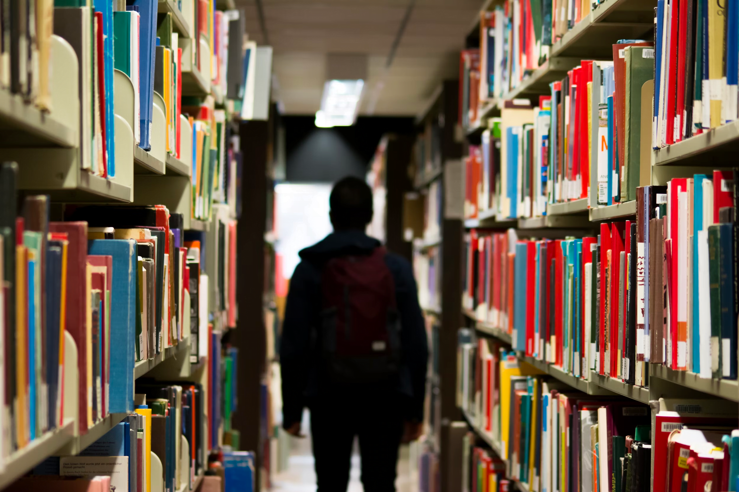 Murid sekolah menengah berjalan di perpustakaan