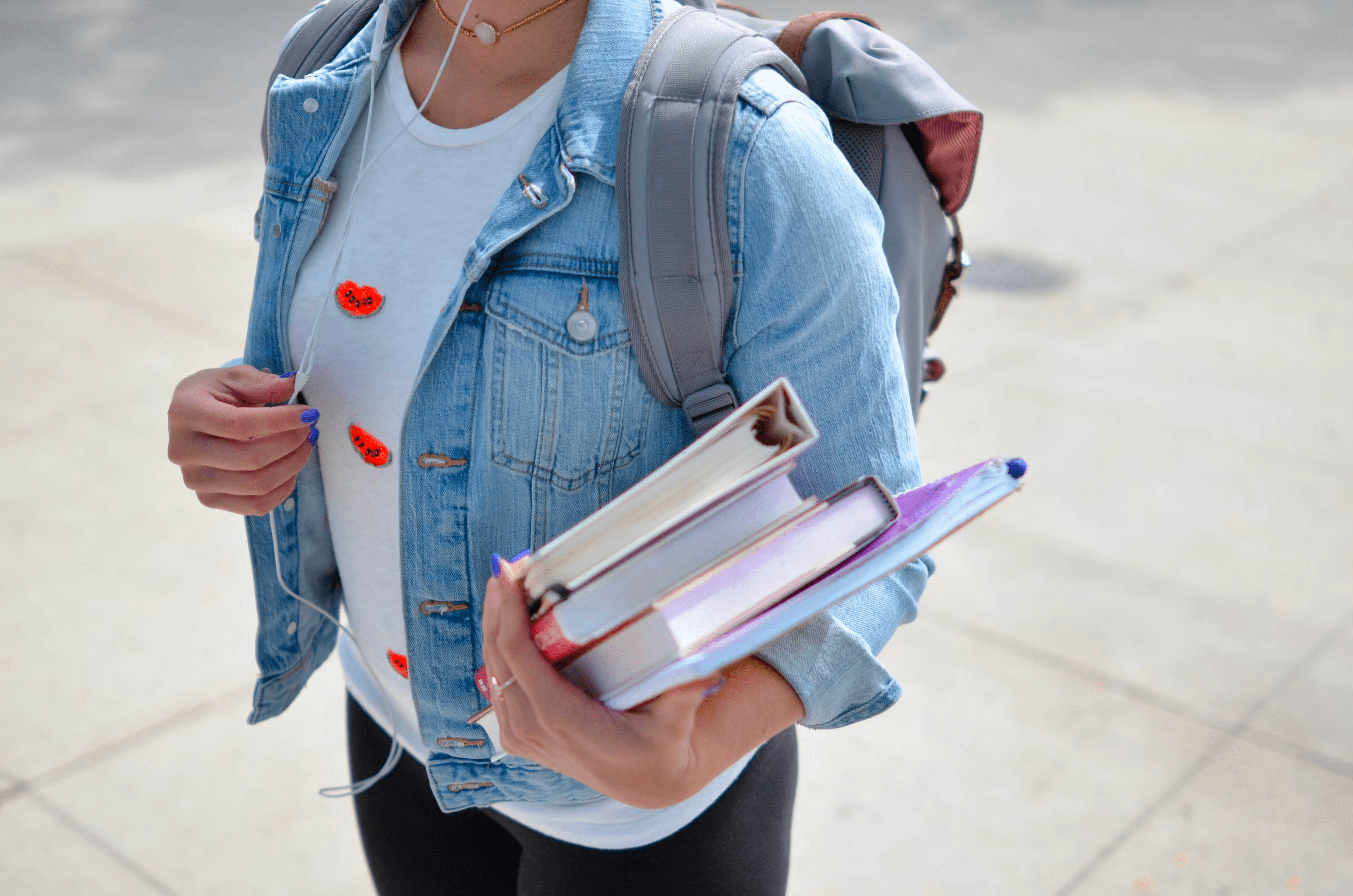 High school student holding books, listening to music